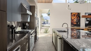 A modern kitchen with a central island, stainless steel appliances, and a view to the outdoors. - Oxygen @ Elemento49 - Pool & Spa - Sleeps 16 (Indio)