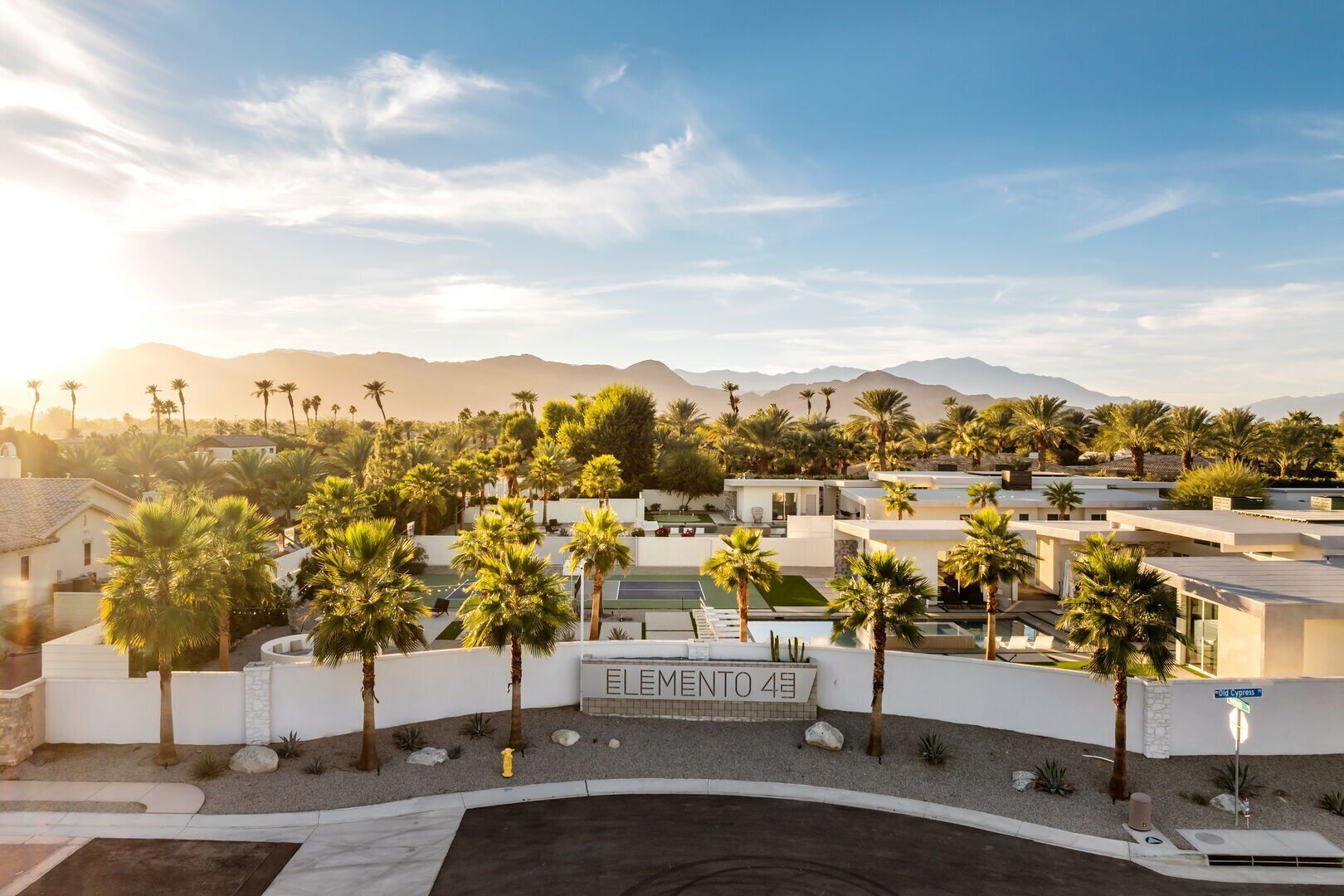 A modern residential area with palm trees, a pool, and a sign reading "ELEMENTO 4".