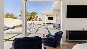 A modern living room with a large glass door leading to an outdoor patio. - Oxygen @ Elemento49 - Pool & Spa - Sleeps 16 (Indio)