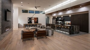 Una sala de estar moderna con chimenea, comedor y cocina con barra.