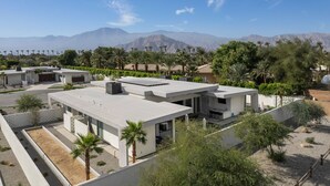 Una zona residencial moderna con varias casas, un estacionamiento y montañas al fondo.
