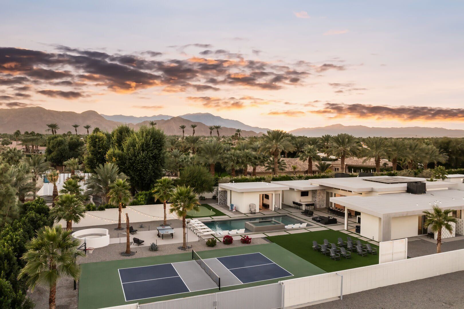 A resort with a pool, tennis courts, and palm trees.