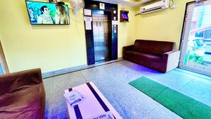A reception area with a television, elevator, and a couch. - Hotel President Inn -near Temple & Beach (Puri)