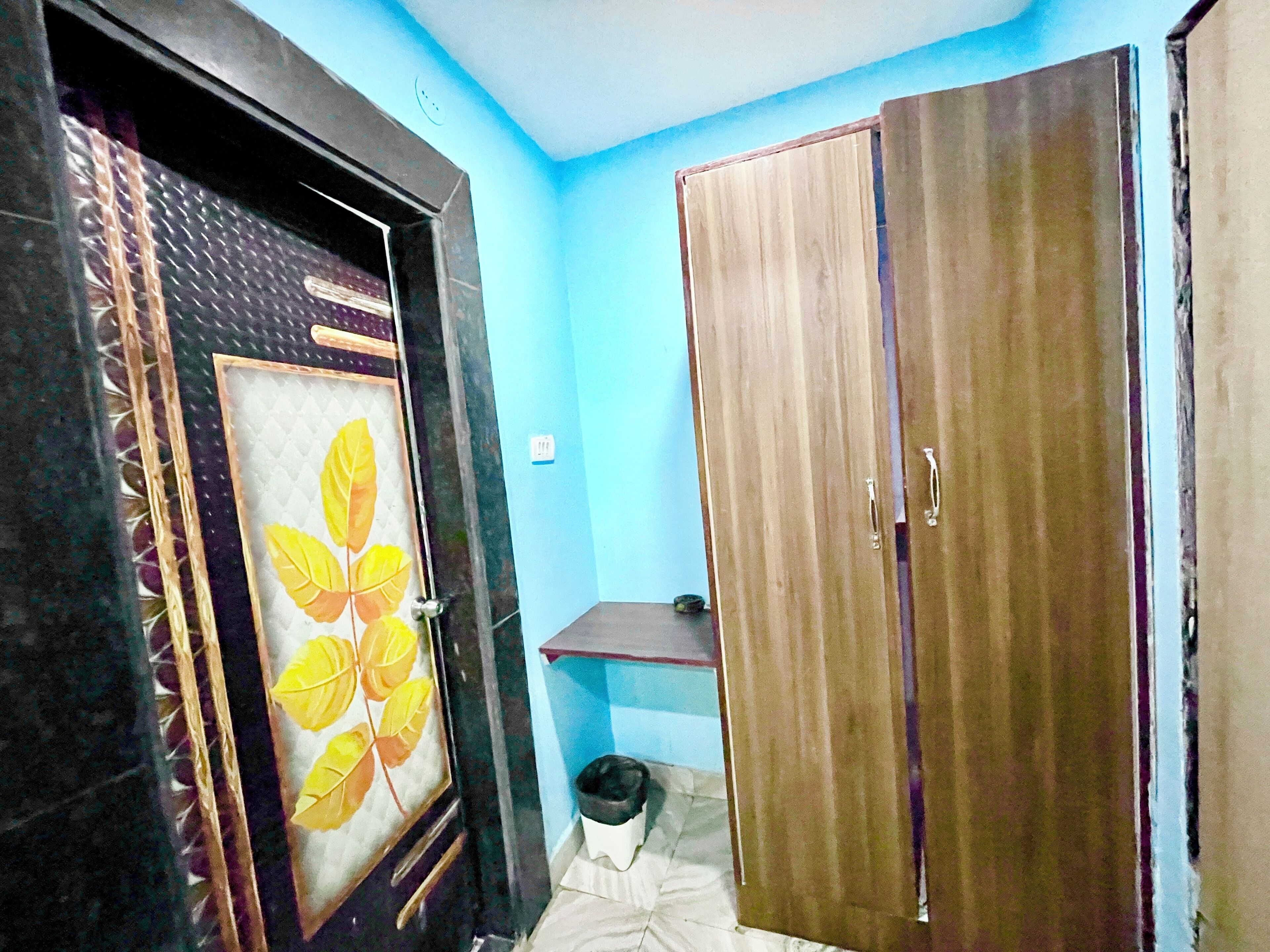 A room with a wardrobe, a bed with a white bedspread, and a wall with a blue paint color.