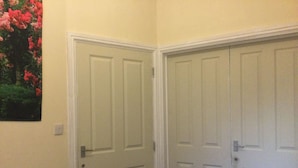A room with two white doors, a white bed frame, and a white chair.