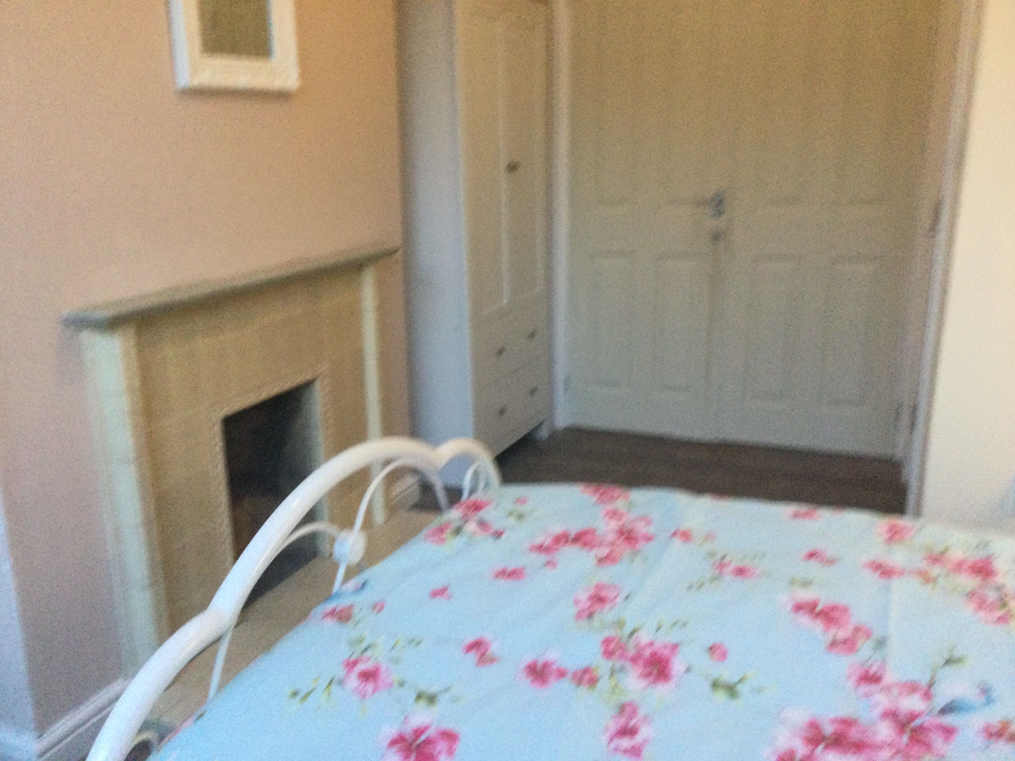 A room with a bed, a white chair, a fireplace, and a door.