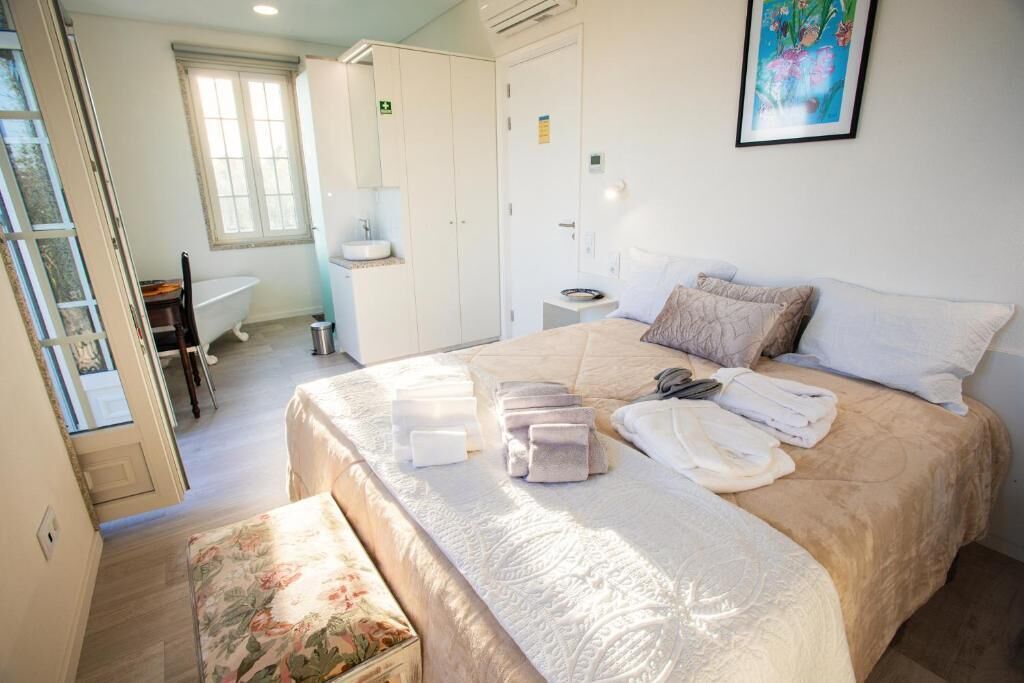 Una habitación de hotel con una cama, una mesita de noche, una ventana, un baño y una puerta.