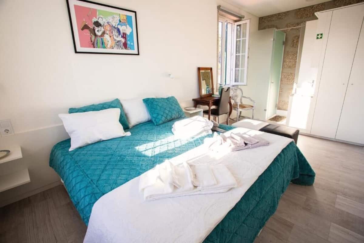 A bedroom with a bed, a desk, a chair, a wardrobe, and a window.