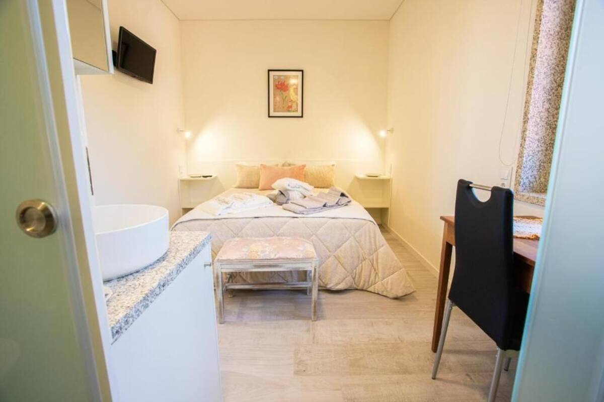 A bedroom with a bed, bedside tables, a desk, and a chair.