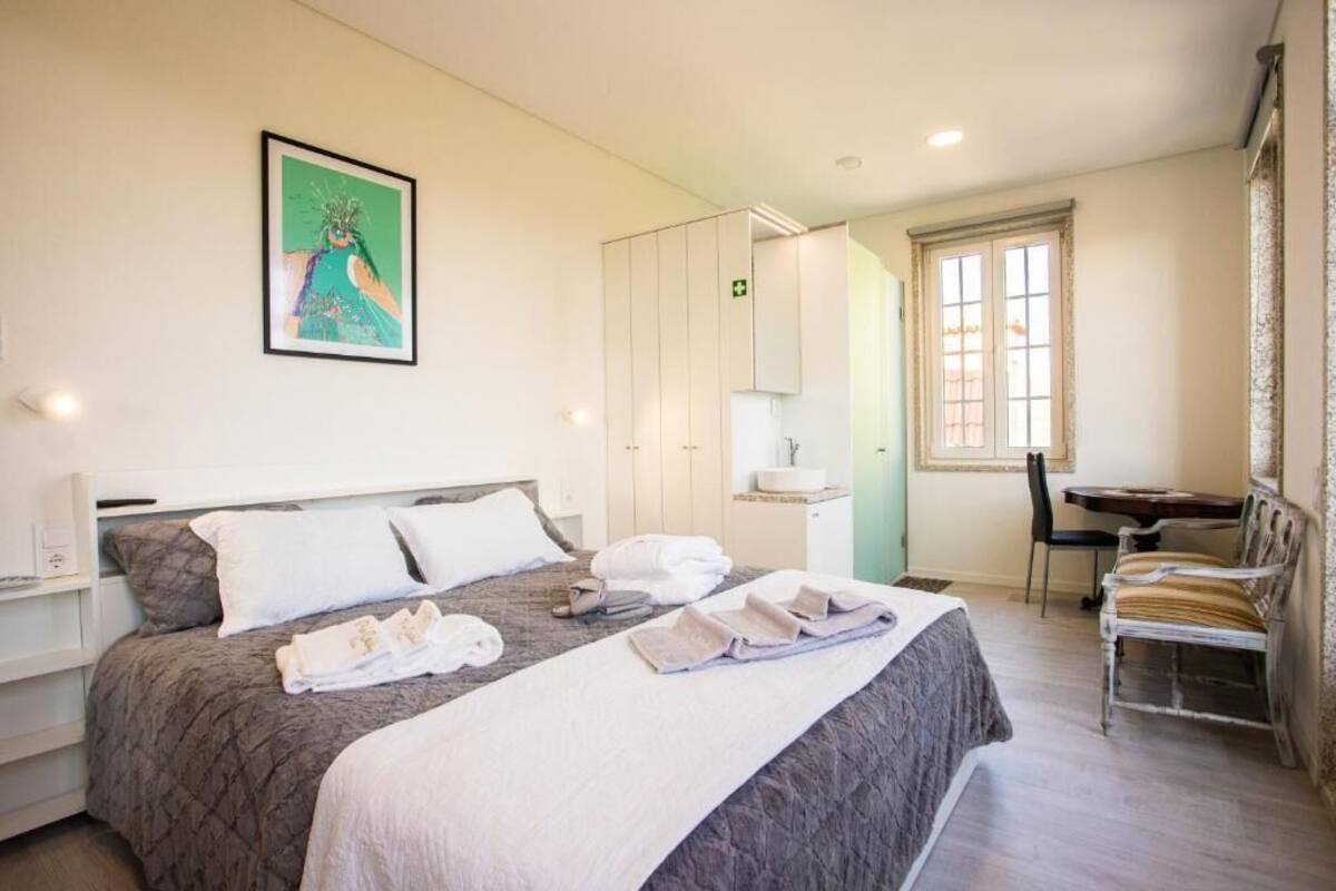 A hotel room with a bed, a desk, a chair, and a window.