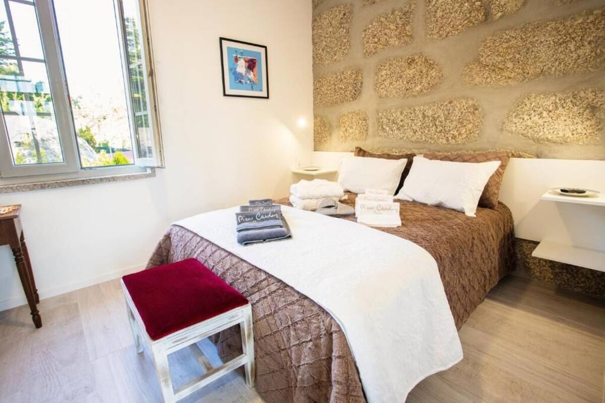 A neatly arranged bedroom with a bed, bedside tables, a window, and a wall with a textured pattern.