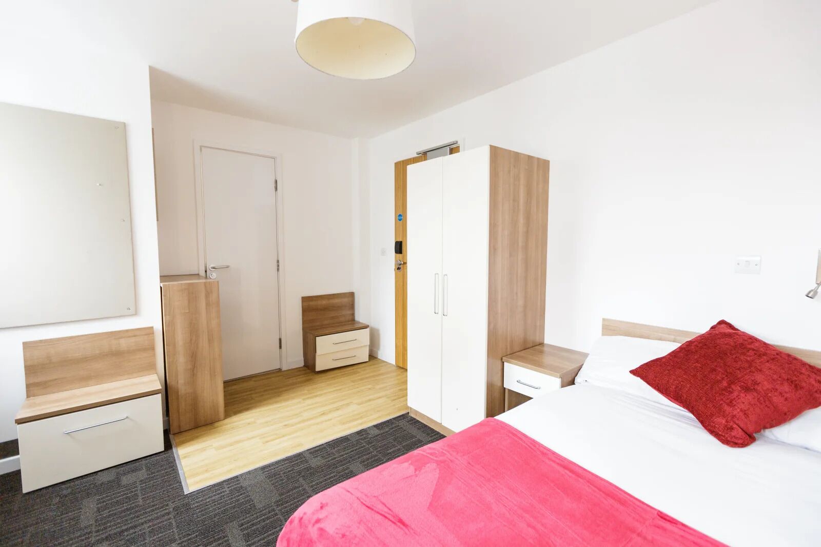 Una habitación de hotel con cama, armario, escritorio y espejo.