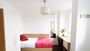 Un dormitorio moderno con cama, escritorio y silla.