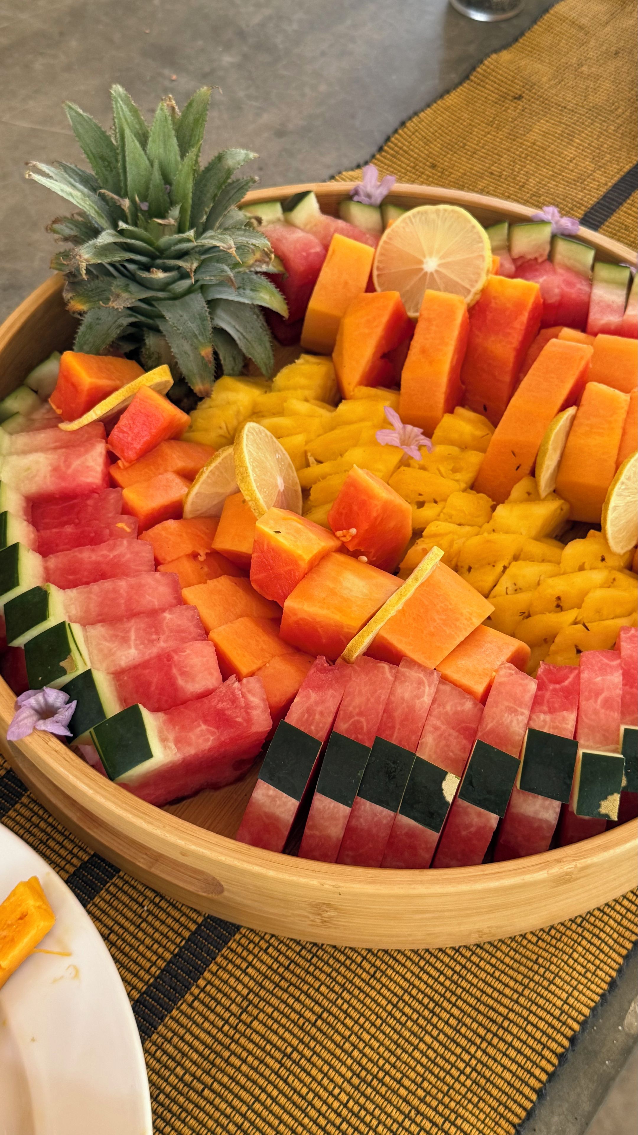 A wooden bowl filled with various fruits and a pineapple.