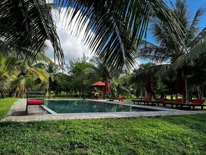 Una piscina al aire libre, sombrillas, sillones reclinables de piscina
