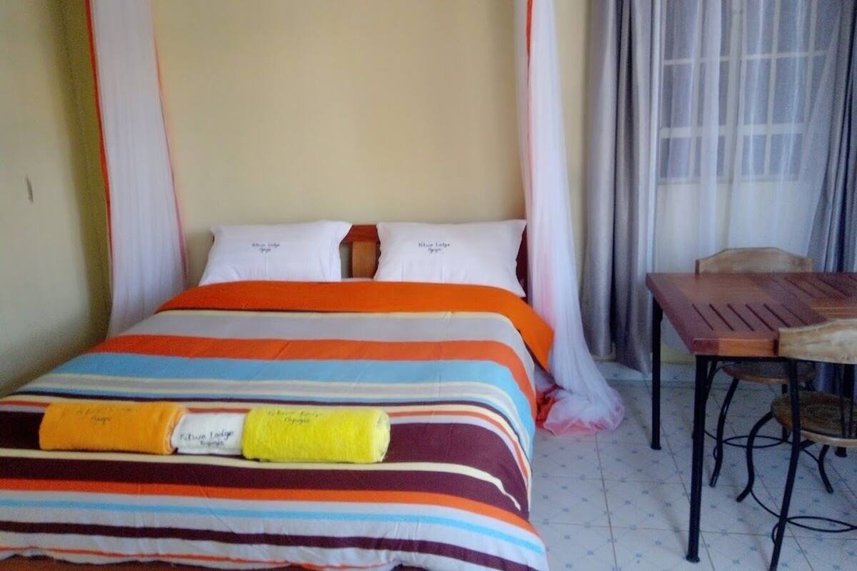 A bed with a striped bedspread, a bedside table, and a chair.