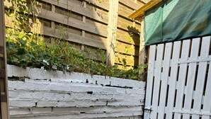 Un espace extérieur aménagé avec une table et deux chaises, un mur en briques blanches et une clôture en bois.