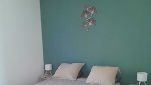 Une chambre à coucher comprenant un lit, deux tables de chevet et un élément décoratif fixé au mur.