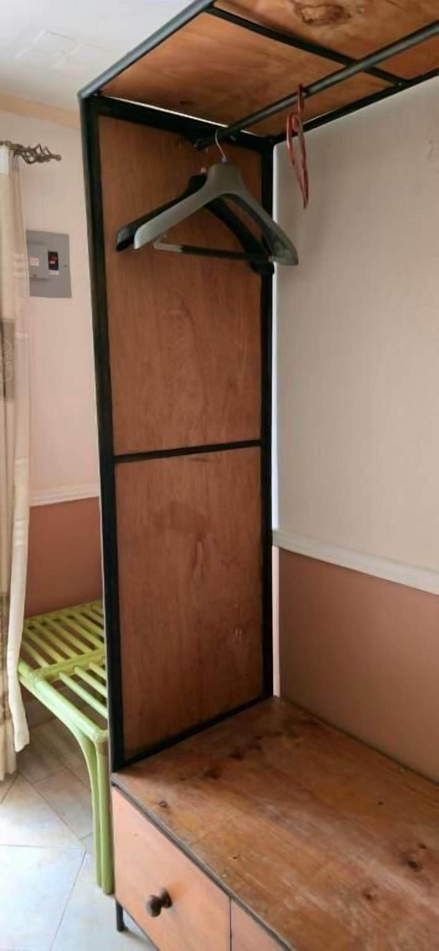 A bunk bed with a wooden frame and a single hanging clothes rack.