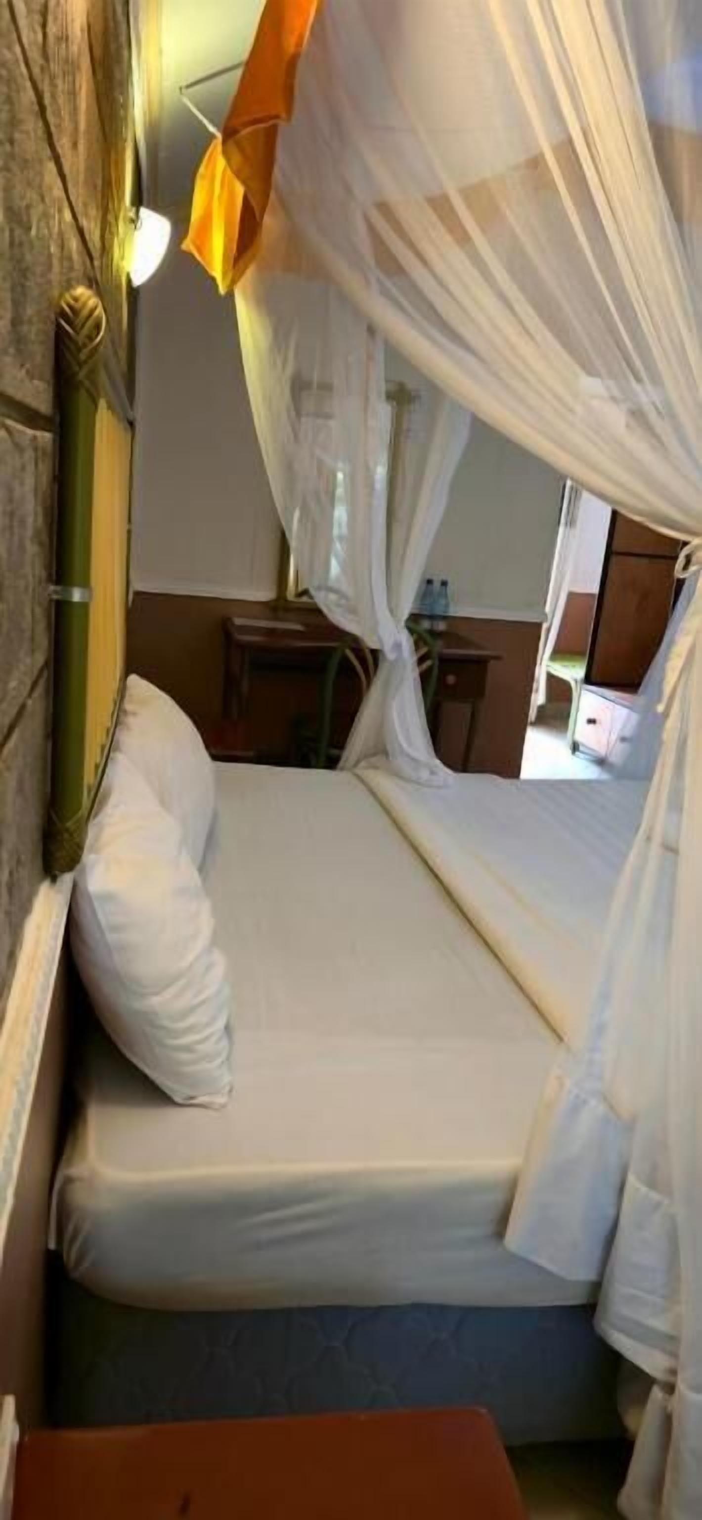 A bed with a canopy, a bedside table, and a lamp.