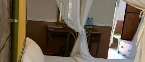 A bed with a canopy, a bedside table, and a lamp.