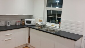Una cocina moderna con armarios blancos, encimera negra y ventana sobre el fregadero.