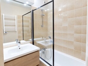 Une salle de bain moderne avec une douche à parois de verre, un lavabo blanc et un miroir.
