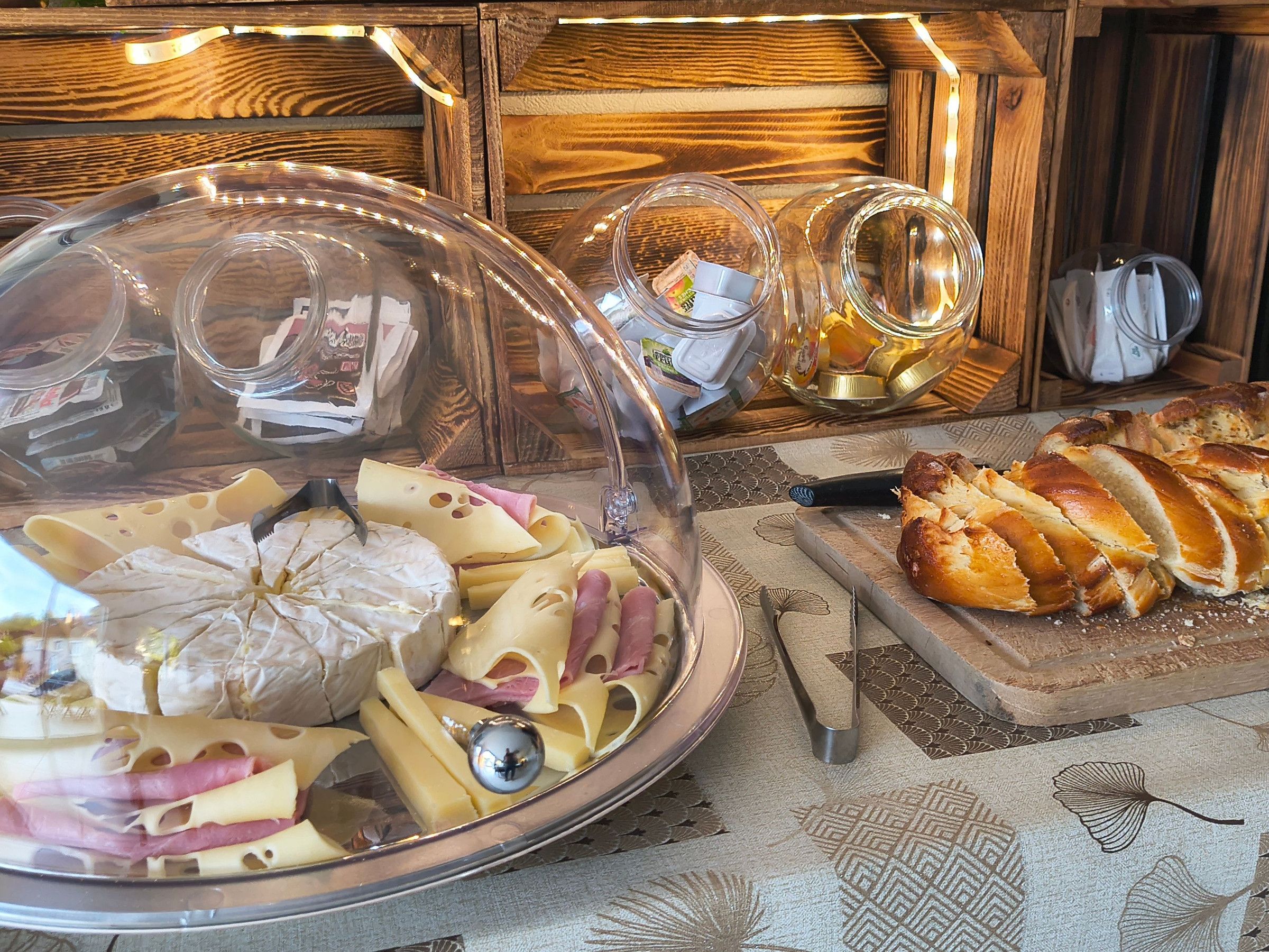 A buffet table with a variety of cheeses, meats, and bread.