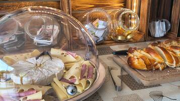 A buffet table with a variety of cheeses, meats, and bread.