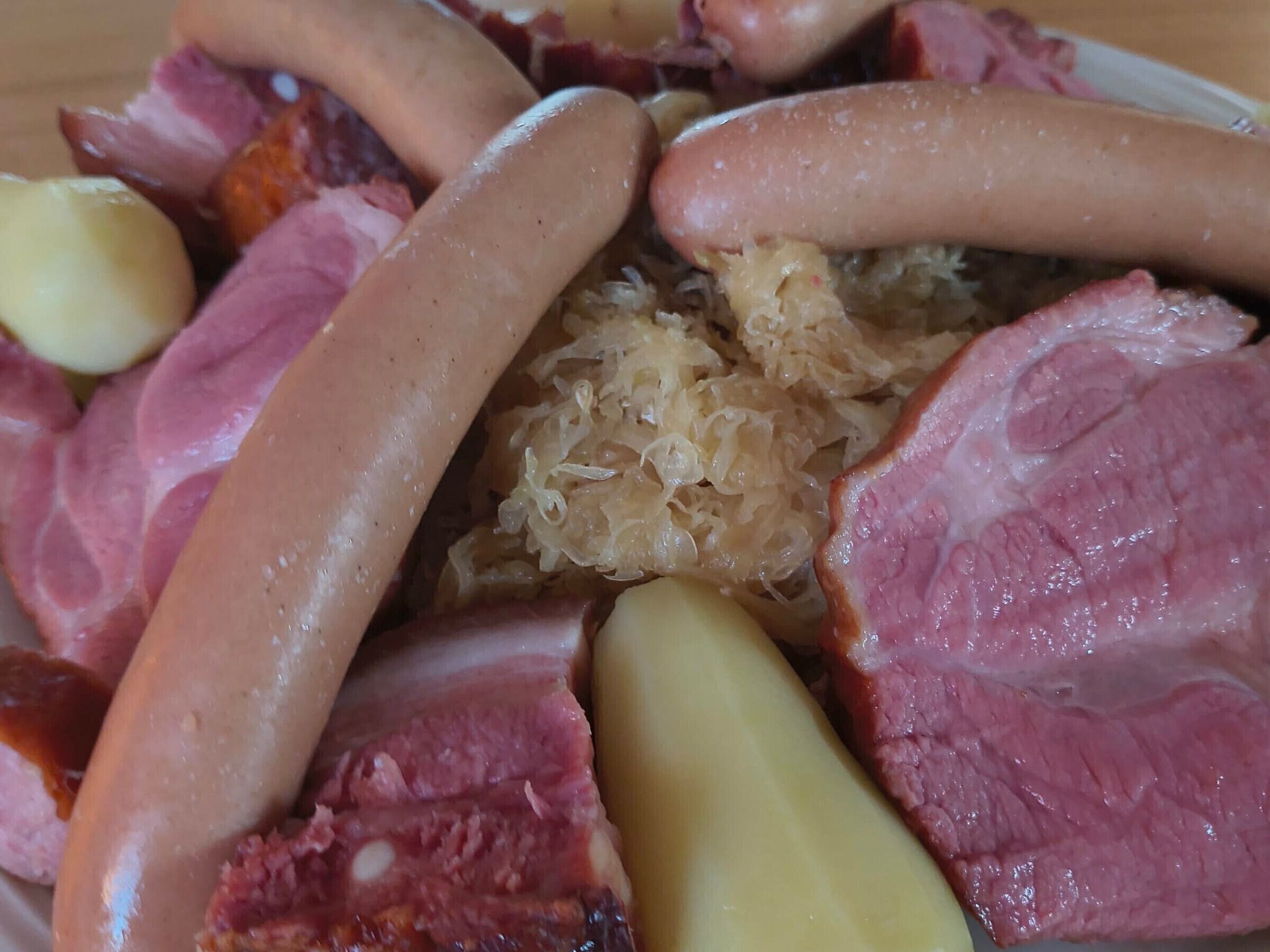 Une variété de viandes, notamment des saucisses, du jambon et, éventuellement, du lard, servies dans une assiette.