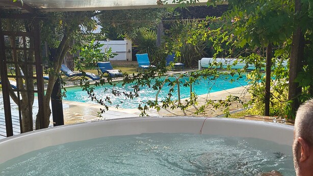 A hot tub with a view of a pool and lounge chairs. - Unique Caravan with Private Nordic Bath in La Flèche (La Flèche)