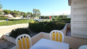 A patio with a table and chairs, a stop sign in the background, and a view of a road with cars and greenery. - Renovated apartment 50m from Grifeu Beach (Llançà)