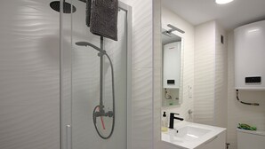A modern bathroom with a glass-enclosed shower, a white sink, and a toilet. - Renovated apartment 50m from Grifeu Beach (Llançà)