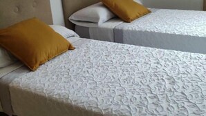 Dos camas individuales con ropa de cama estampada, cabeceros y almohadas color mostaza.