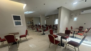 Un comedor amplio con varias mesas y sillas, unidades de aire acondicionado y cuadros en las paredes.