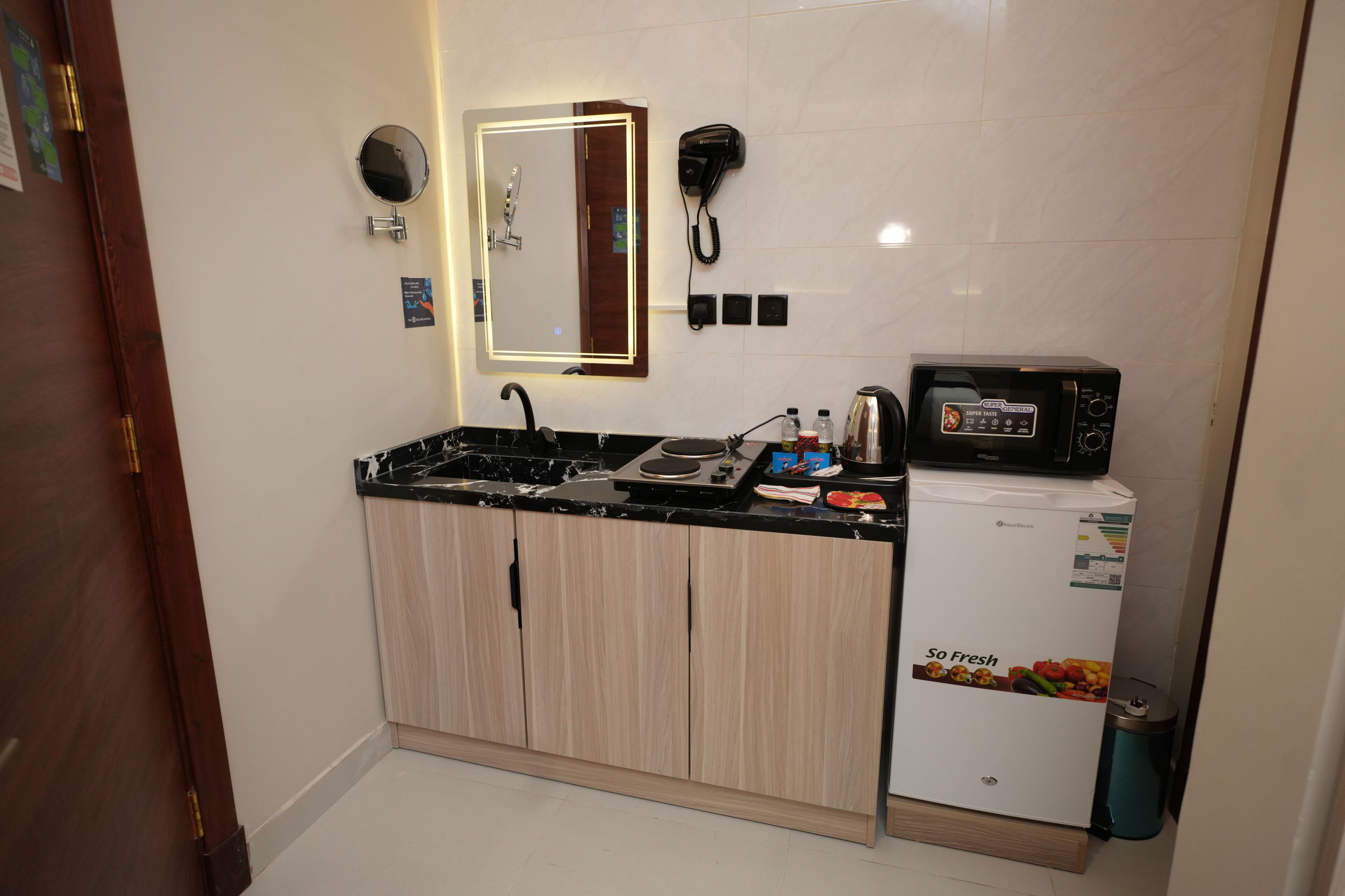 A compact kitchen with a black countertop, a built-in microwave, and a small refrigerator.
