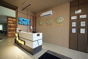 Un comptoir d’accueil doté d’un écran numérique, d’horloges, de certificats et d’un climatiseur fixé au mur.