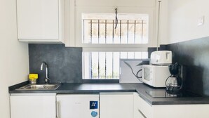 Une cuisine compacte équipée d’un évier, d’un four à micro-ondes et d’une machine à café.