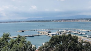 Un port de plaisance avec des bateaux amarrés, un ciel dégagé et des montagnes à l’horizon.