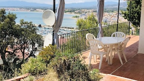 Une terrasse avec une table et des chaises, donnant sur une marina et une ville côtière.