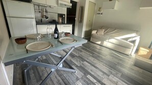 Une cuisine moderne avec une table à manger en verre, des meubles blancs et un plancher en bois gris.