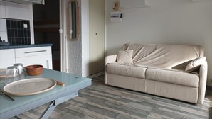 Une cuisine moderne avec un plan de travail en verre, un canapé beige et un plancher en bois.