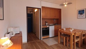 Una cocina compacta con armarios de madera, una mesa de comedor con sillas y un refrigerador pequeño.