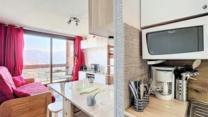 Ett kompakt bostadsutrymme med ett litet kök, en matplats och en soffa.