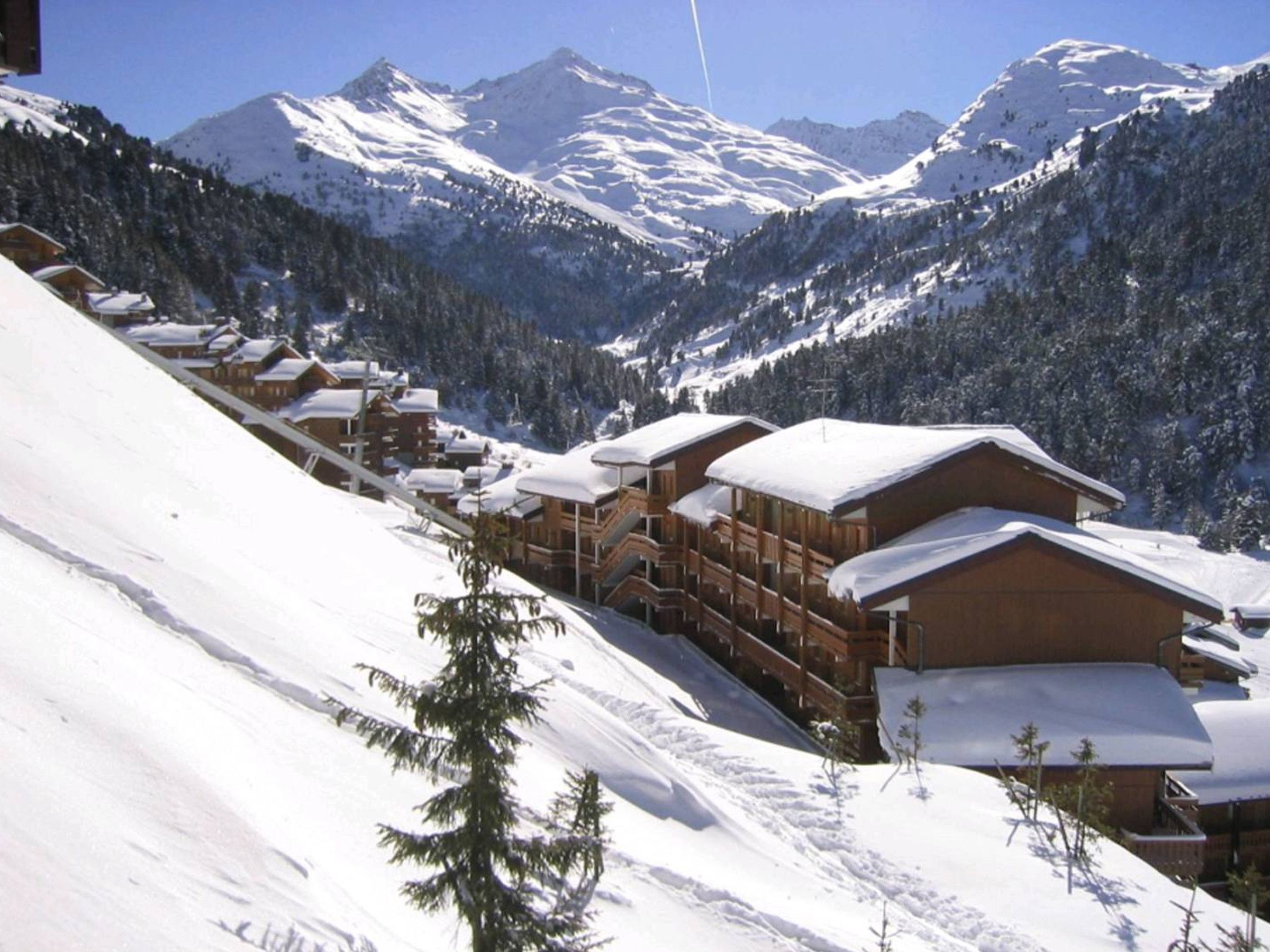 A snow-covered mountain resort with wooden cabins and a ski slope.