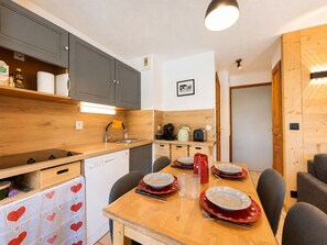 A compact kitchen with a wooden table set for four, equipped with a sink, a kettle, and a toaster. - Cozy studio cabin at ski slopes, 4 pers, balcony (Notre-Dame-de-Bellecombe)