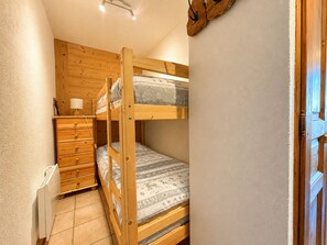 Habitación con literas, cómoda de madera, lámpara y radiador.