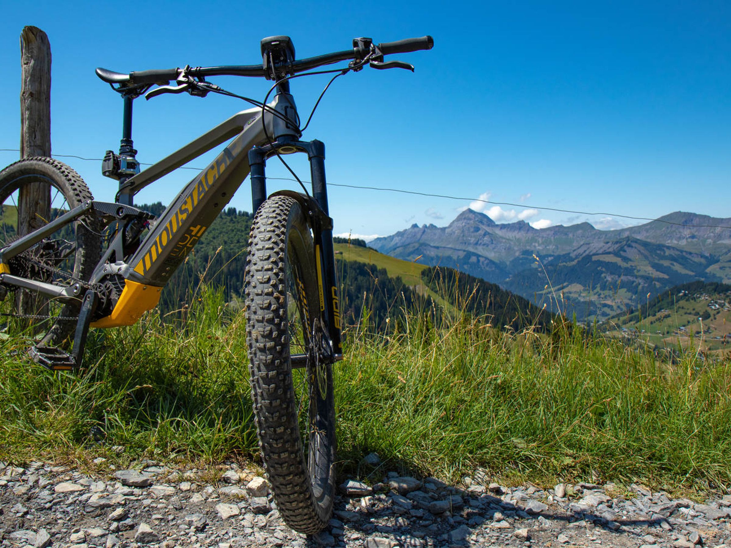 Een mountainbike geparkeerd op een grindpad, met een prachtig uitzicht op de bergen op de achtergrond.