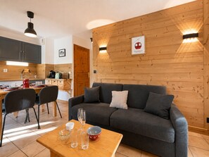 Una sala moderna con un sofá gris, una mesa de centro de madera y un comedor con una mesa y sillas de madera.