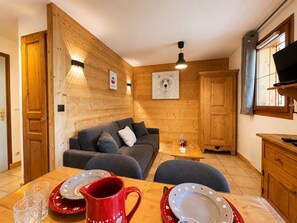 A cozy room with a wooden interior, a sofa, a dining table with plates and glasses, and a television.